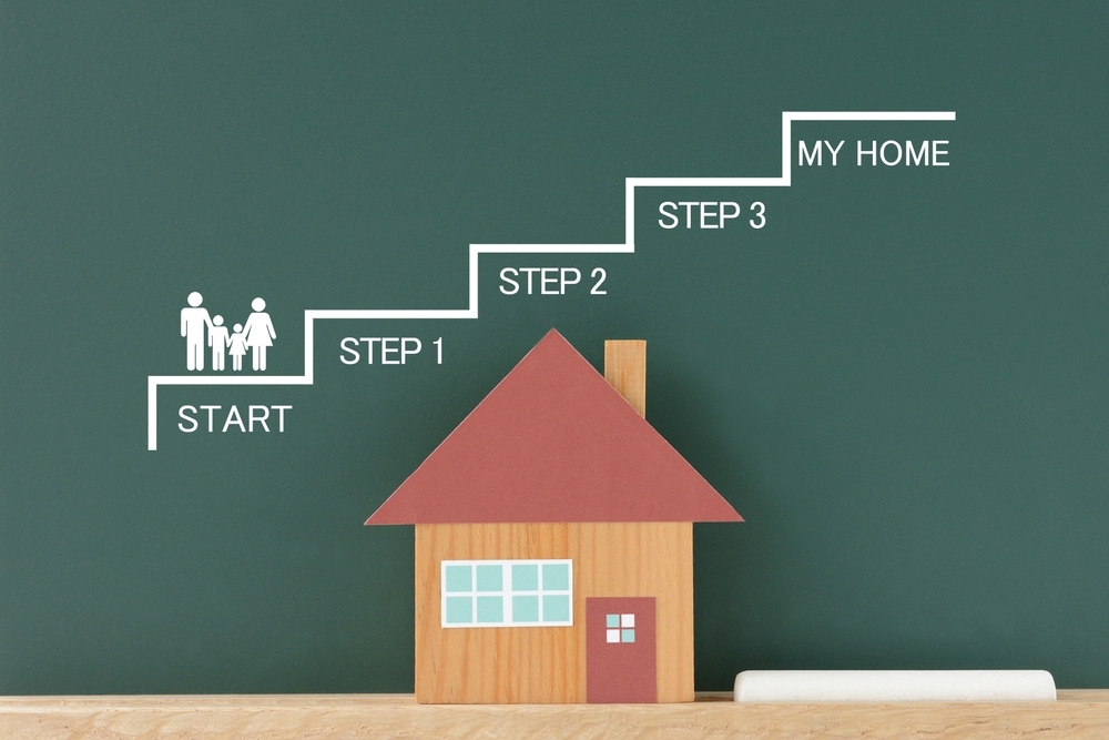 Wooden house with a red roof and a chalk-drawn staircase with labelled steps, illustrating the importance of having a timeline when planning and building a custom home.