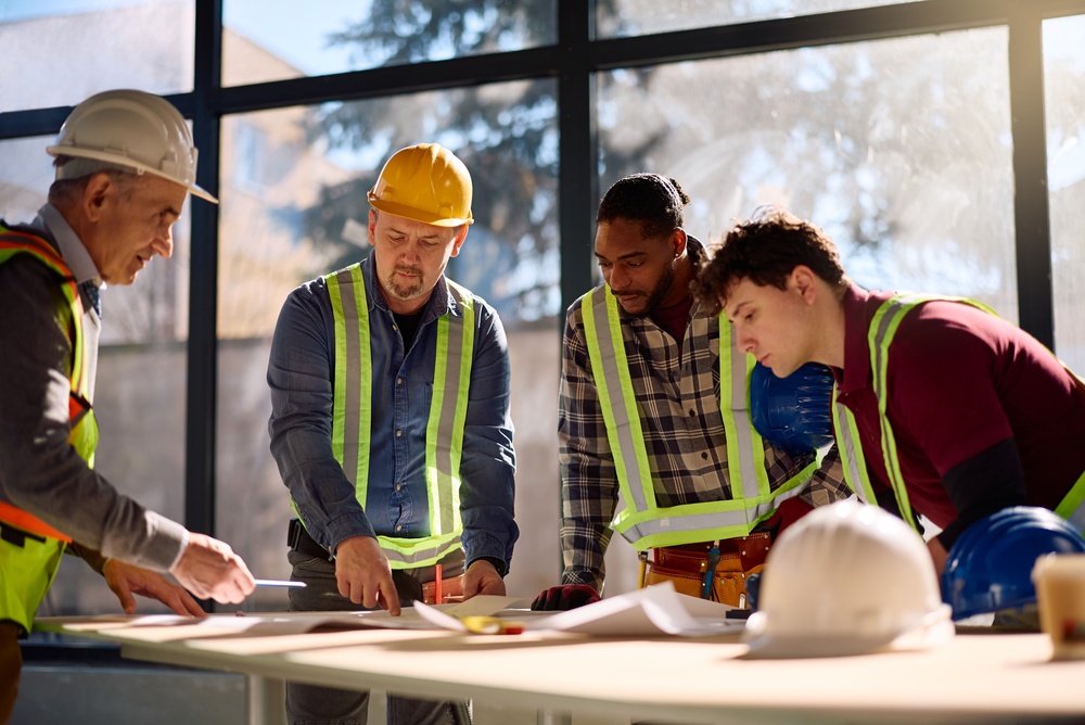 Image of construction workers gathered around a table looking at a blueprint.